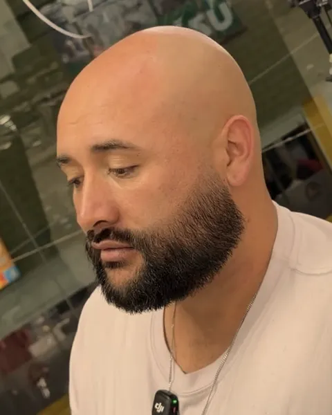 Barba completa y bien perfilada en un cliente de cabeza rapada.