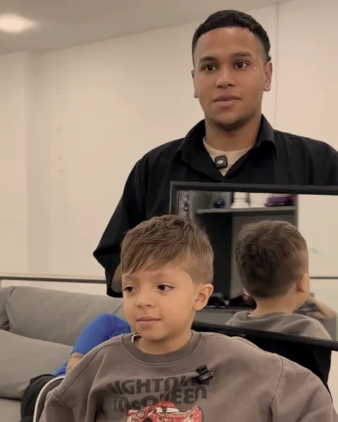 Niño sentado en la silla junto a su barbero, listo para el corte.